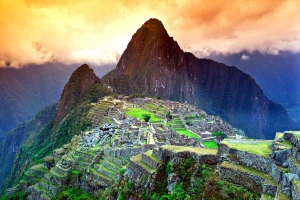 De Incastad Machu Picchu met de berg Huayna Picchu onder een oranje gekleurde lucht