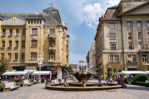 Fontein met vissenbeelden op het plein Piața Victoriei in Timișoara, tussen statige gebouwen